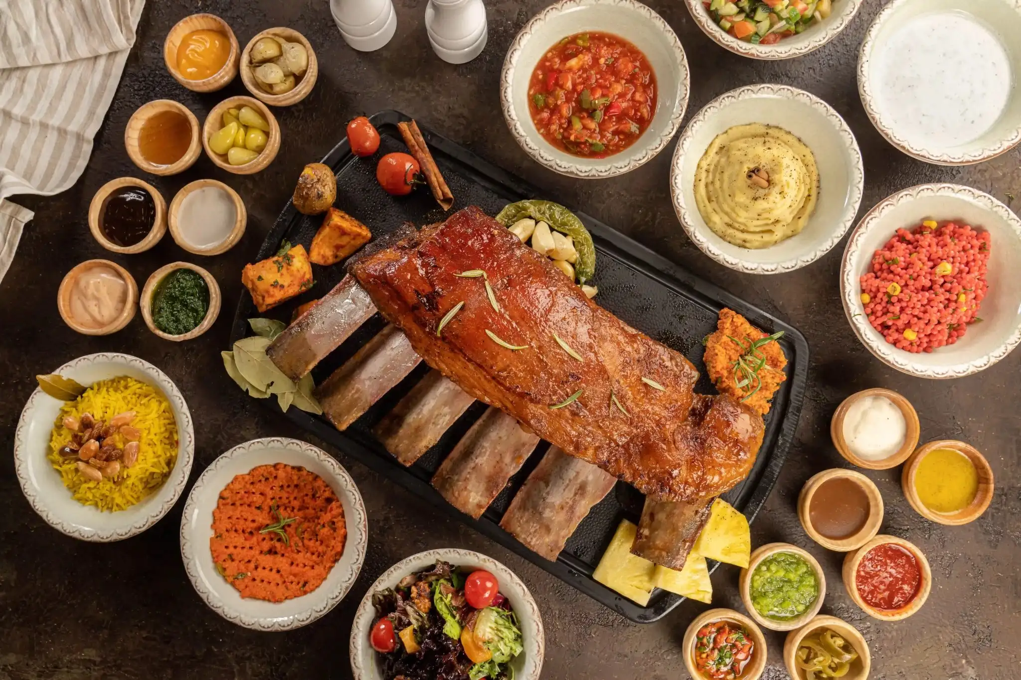 A shared spread of halal smoked beef ribs, salads and sauces for a group at Meat Moot
